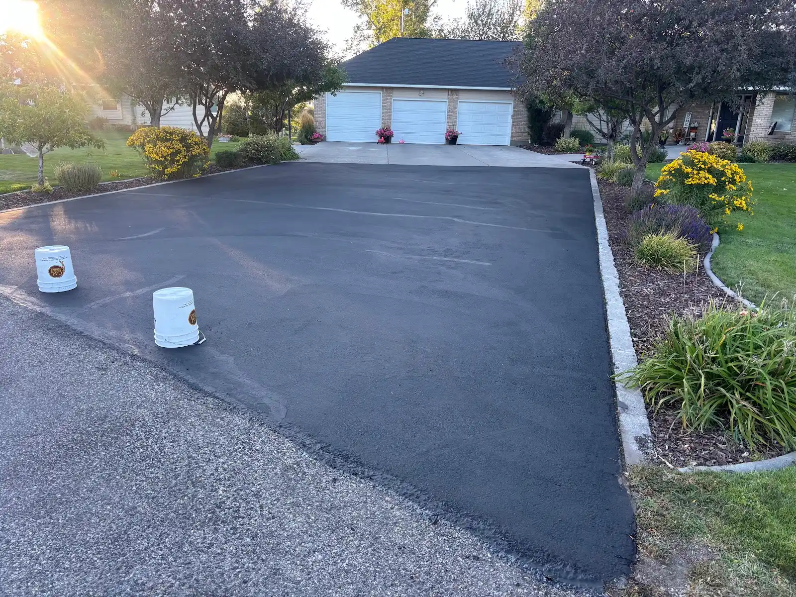 A freshly finished asphalt driveway beside a home.