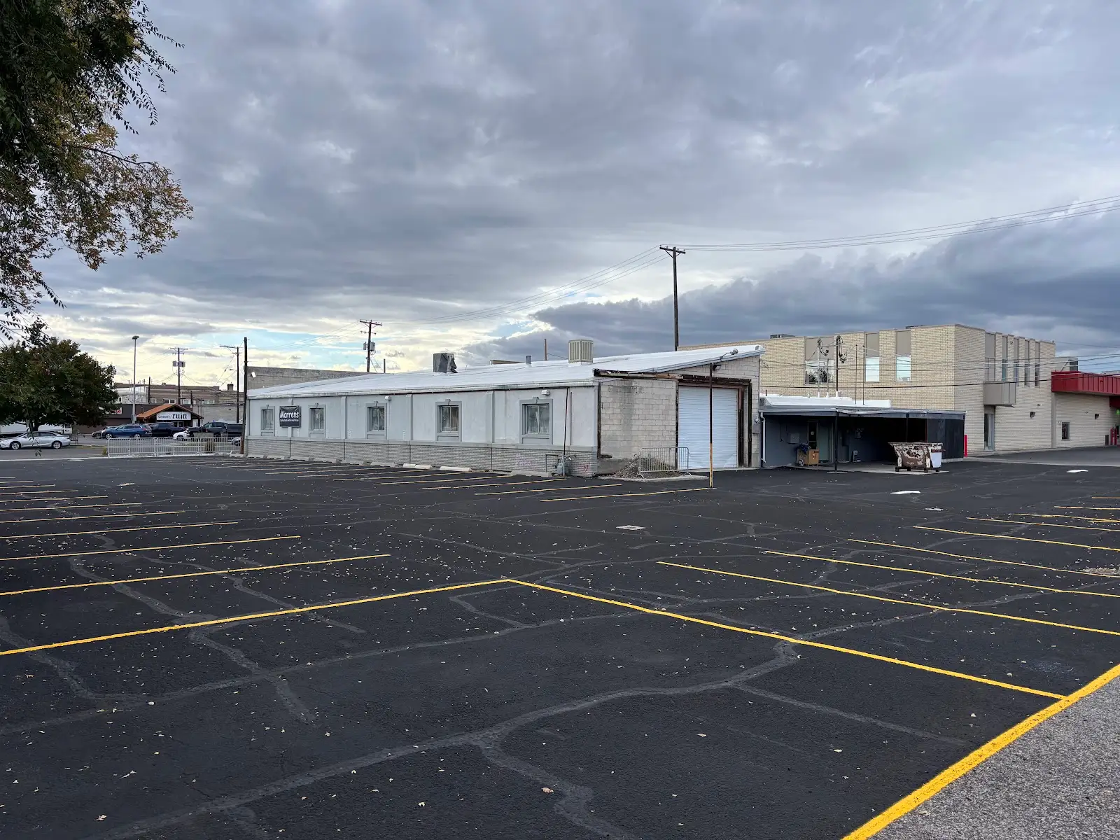 Asphalt parking lot with yellow parking lines and buildings in the background.